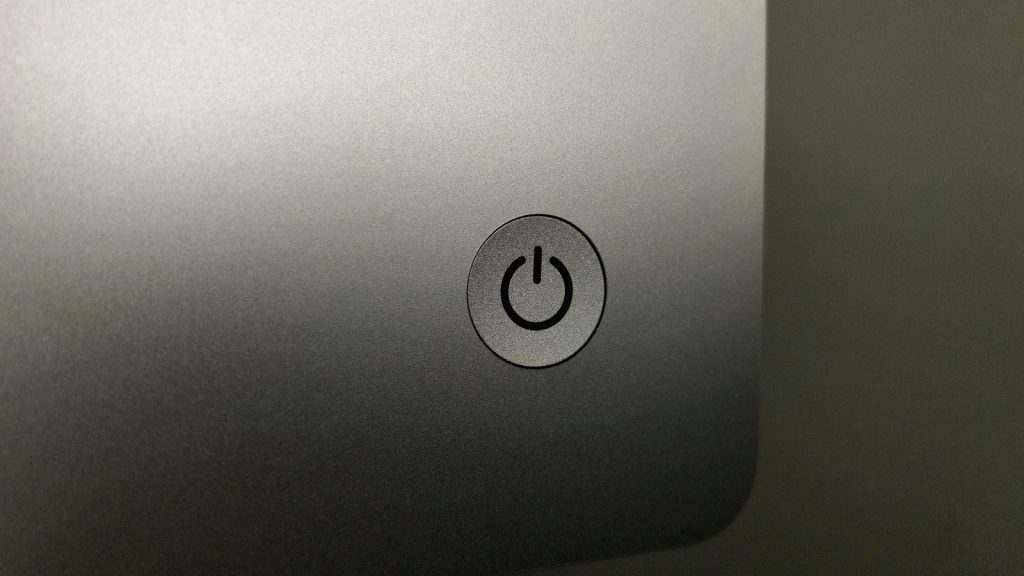 Power button on the back of a silver desktop computer.