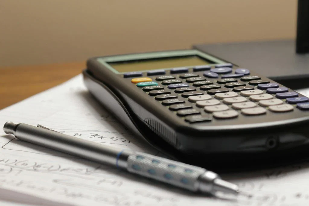 A calculator and pen on financial paperwork, illustrating household spending administration.