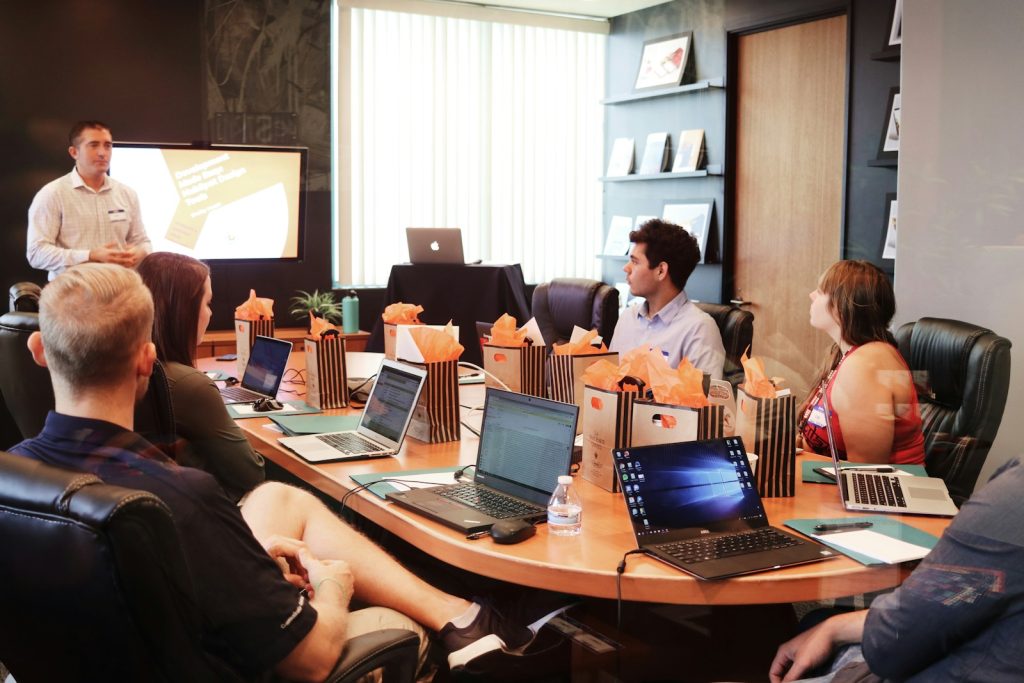 Office team meeting around a table with laptops, representative stock photograph